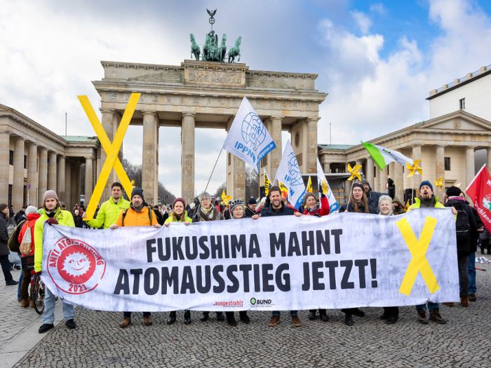 Eine Gruppe Menschen steht mit einem Banner vor dem Brandenburger Tor. 