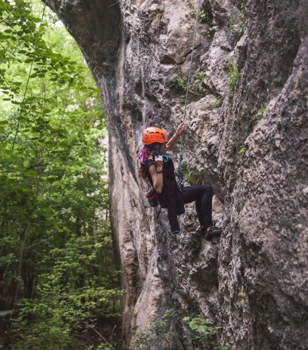 Eine Frau klettert mit einem Kletterseil an einem Felsen. 