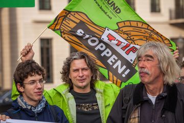 BUND-Mitarbeiter hält Fahne mit dem Slogan "TTIP stoppen" hoch