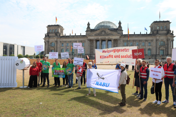 Menschen protestieren mit Schildern vor dem Reichstag.